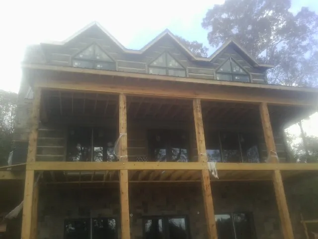 Dormers and porch framing on a large log home under construction — Roof Coating work by our crew in Verndale