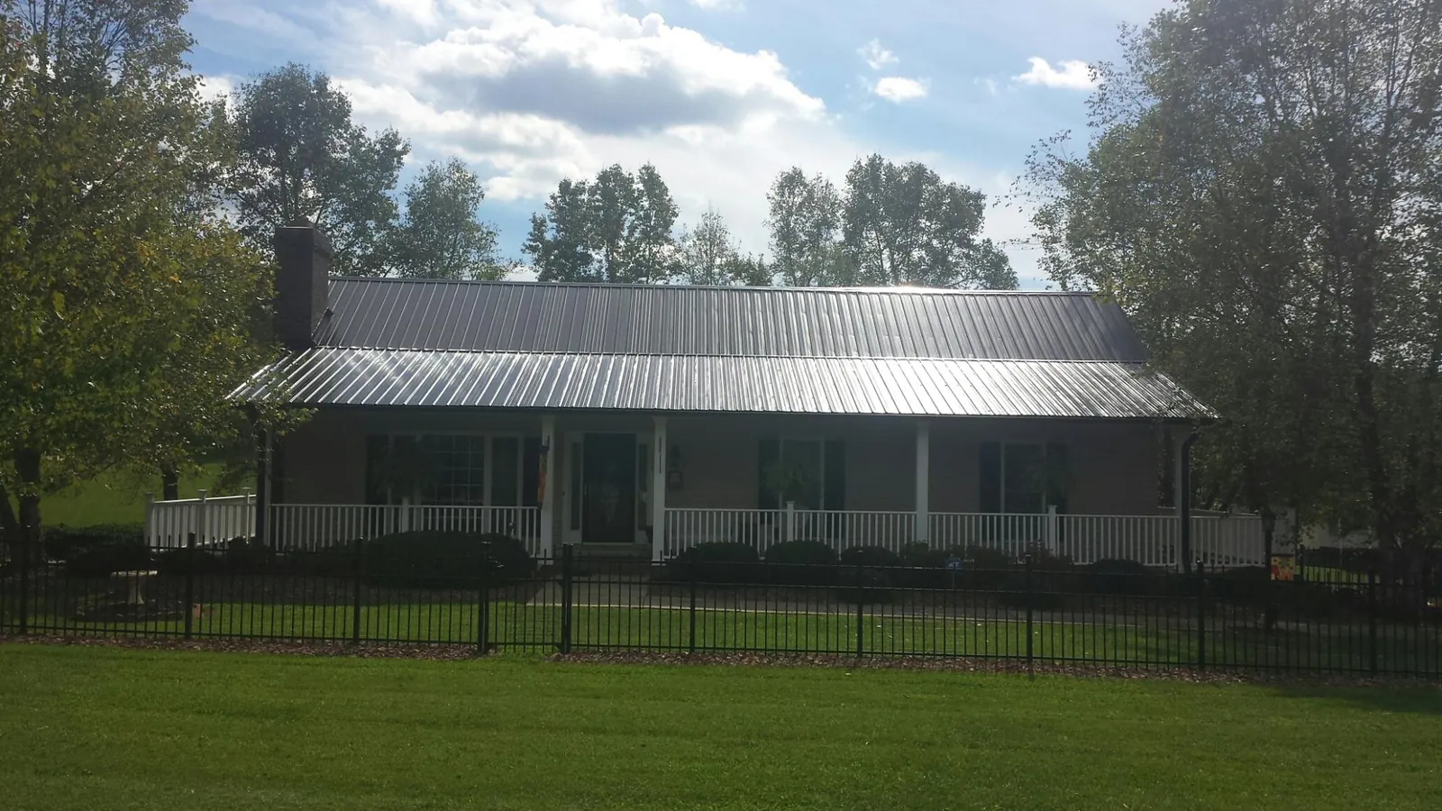 Gray metal roof on a brick ranch with a full width front porch — Gutter Guard Installation work by our crew in Verndale